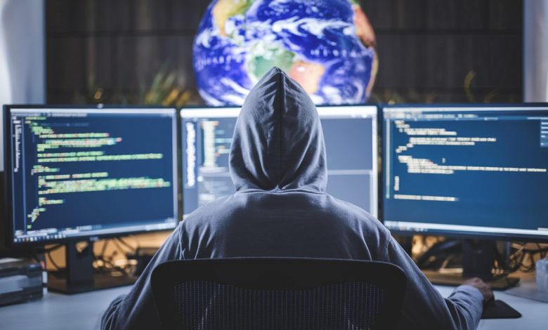 Un hacker travaillant devant plusieurs écrans dans une ambiance sombre